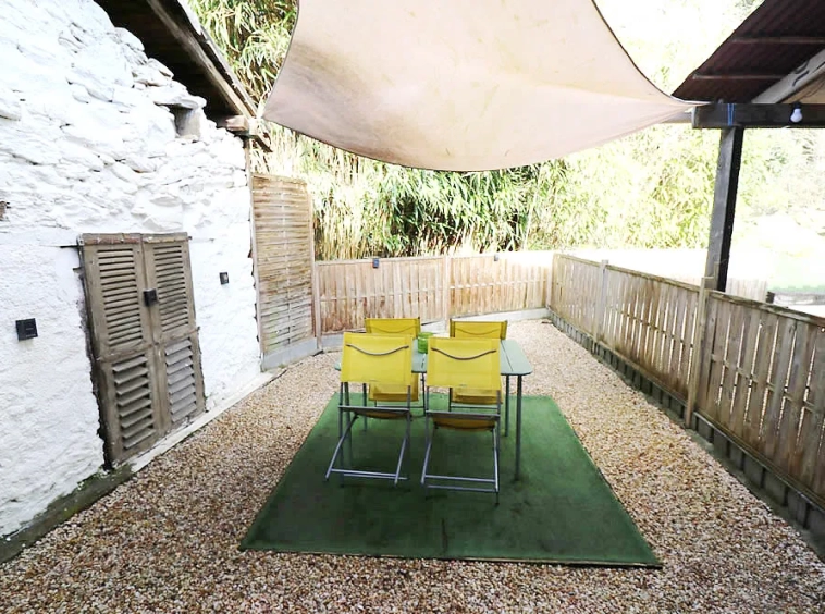 Outdoor patio with chairs and shade canopy.