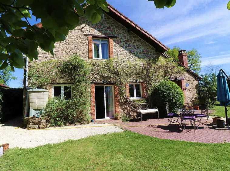 Stone cottage with garden and outdoor seating.
