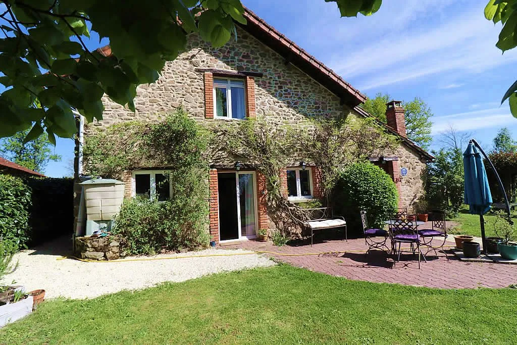 Stone cottage with garden and outdoor seating.