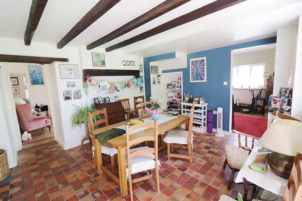 Cosy dining room with wooden beams and tiled floor.