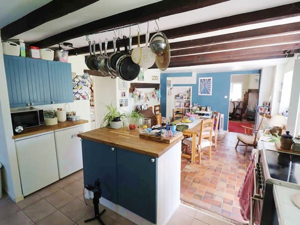 Cosy rustic kitchen with hanging pots and dining area.