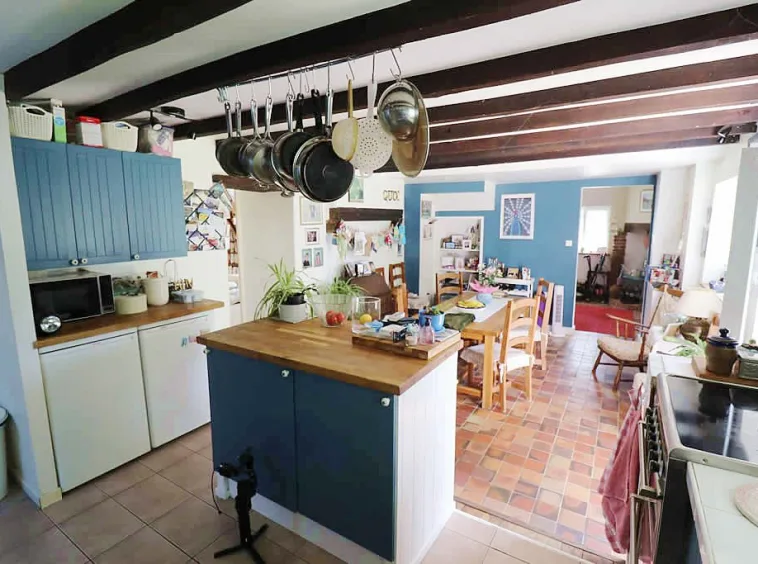 Cosy rustic kitchen with hanging pots and dining area.