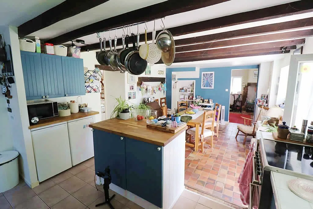 Cosy rustic kitchen with hanging pots and dining area.