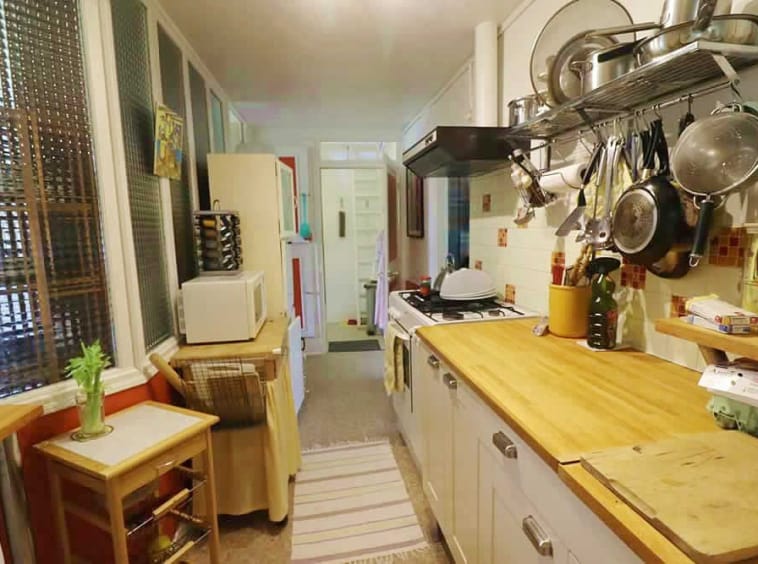 Narrow kitchenette with kitchenware and wooden worktops.