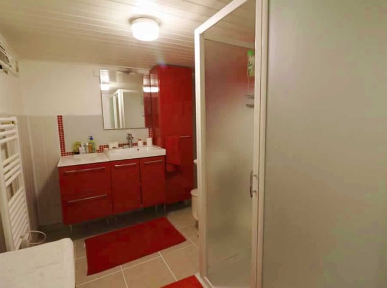 Modern bathroom with red cabinets and glass shower.