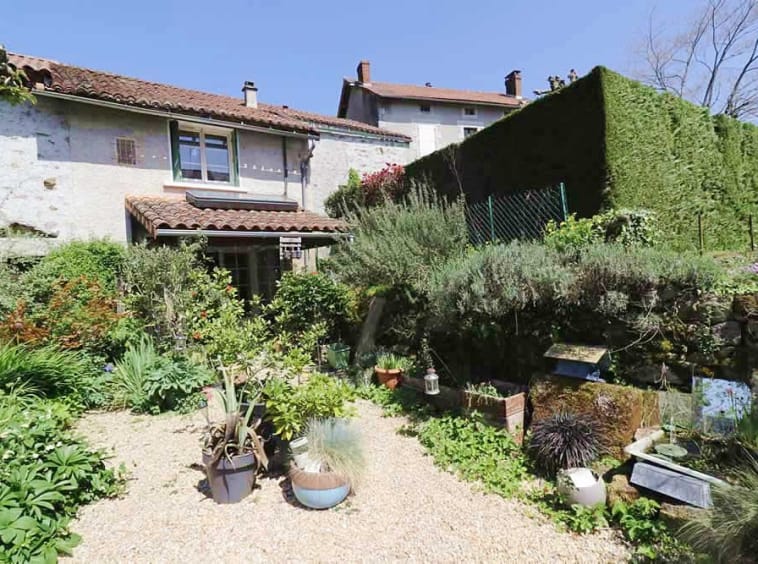 Cottage garden with lush greenery and pebble path.