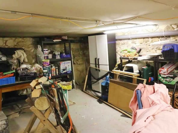 Cluttered basement storage area with shelves and tools.
