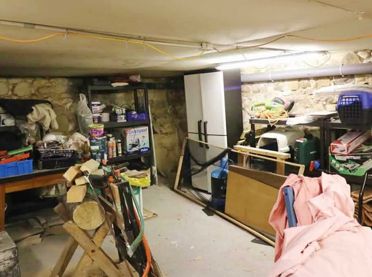 Cluttered basement storage area with shelves and tools.