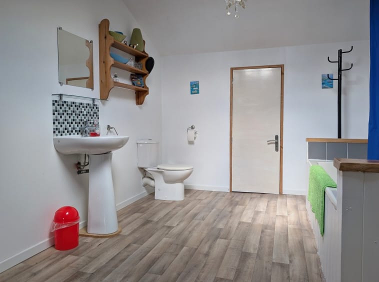 Spacious bathroom with modern fixtures and wooden flooring.