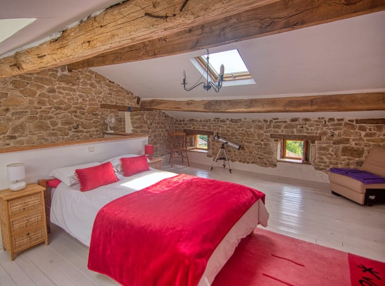 Cosy loft bedroom with telescope and stone walls.