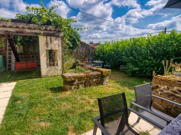 Quaint garden with stone well and patio seating.
