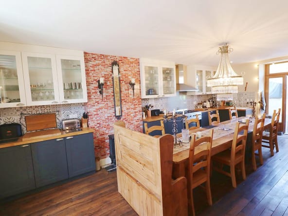 Spacious kitchen with wooden table and chandelier.