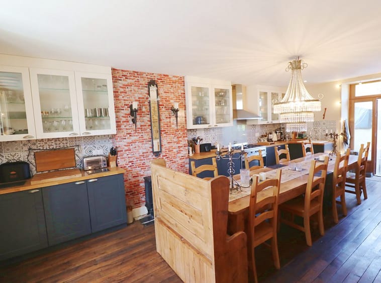 Spacious kitchen with wooden table and chandelier.