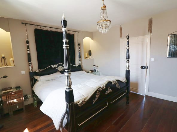Elegant bedroom with four-poster bed and chandelier.