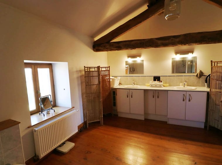 Spacious bathroom with wooden beams and double sinks.