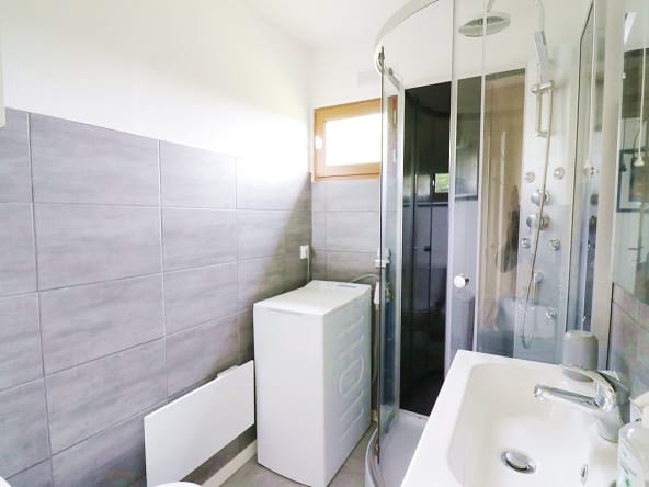 Salle de bain compacte et moderne avec douche et machine à laver.