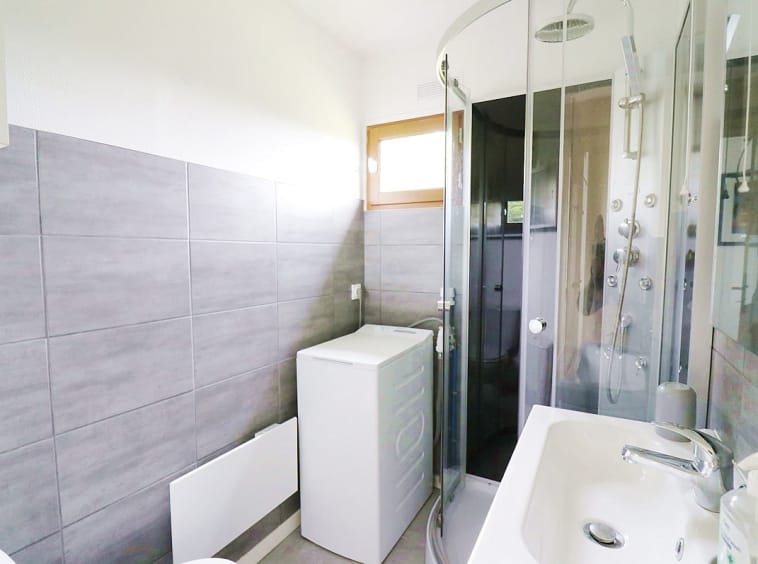 Salle de bain compacte et moderne avec douche et machine à laver.