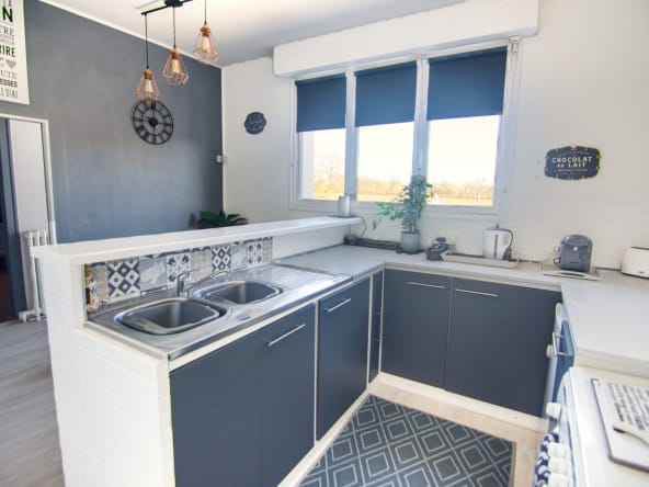 Modern kitchen with grey cabinets and large windows.
