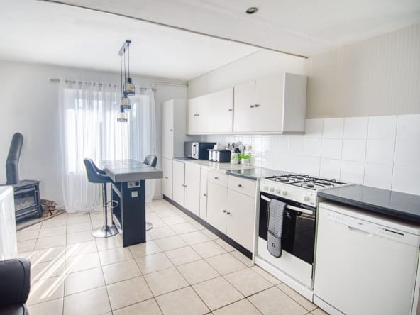 Modern white kitchen with breakfast bar and appliances.