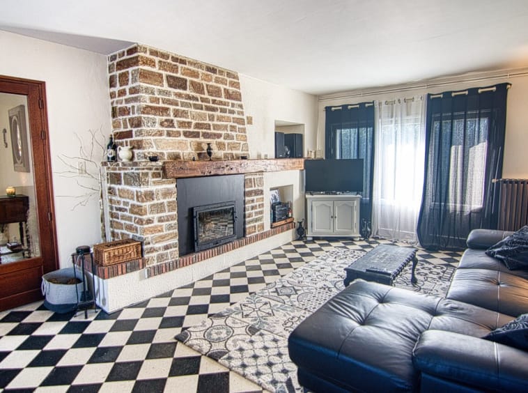 Cosy living room with brick fireplace and black sofa.