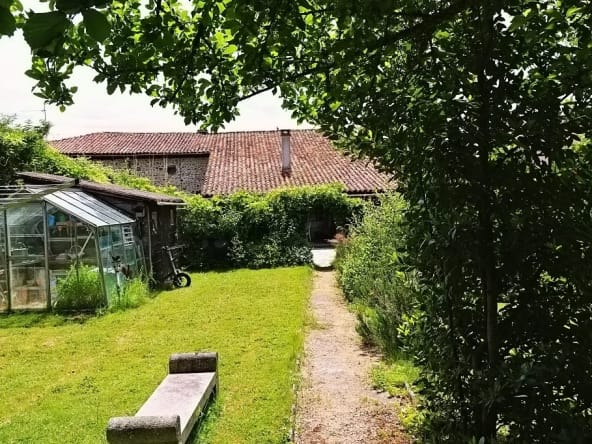 Lush garden with greenhouse and stone pathway