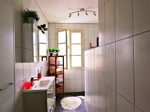 Modern bathroom with tiled walls and natural light.