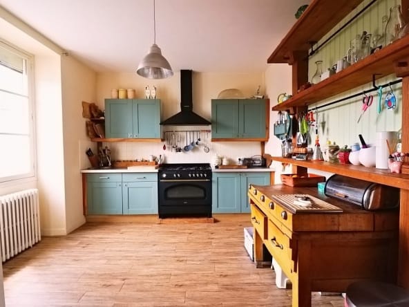 Rustic kitchen with teal cabinets and wooden shelves.